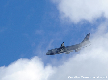 A large passenger jet is partially obscured by clouds during take off.