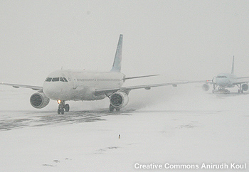 A commercial jet taking off in heavy snow from a snow-covered runway.