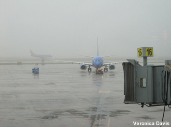 Una aeronave se acerca a la terminal. En la niebla, se entrevé otro jet que está a punto de despegar.