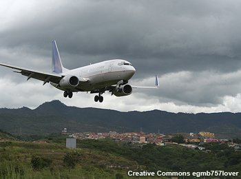 Una aeronave de pasajeros aproximándose al aeropuerto de una zona de montaña. Se notan nubes grises y bajas en el cielo.