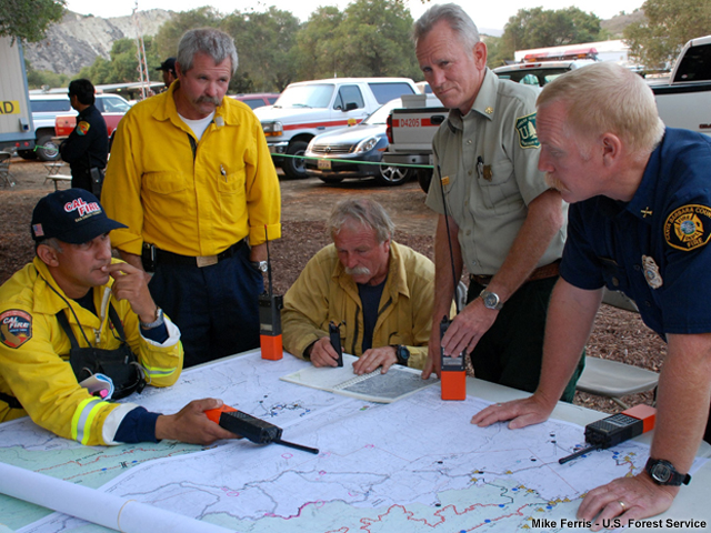 Fire managers and fire fighters planning preparations for the remainder of the day over maps.