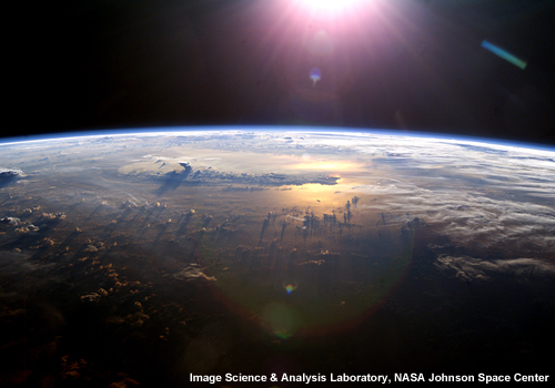 Foto de la puesta del Sol al horizonte sobre el Pacífico tomada desde el Estación Espacial Internacional. Se notan los yunques de algunas tormentas.