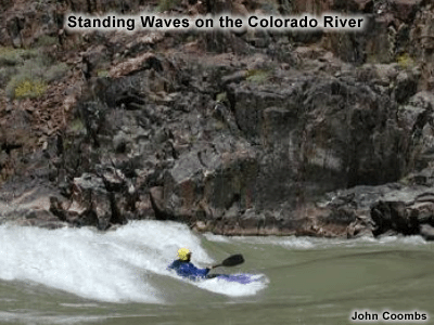 photo of kayaker surfing on a standing wave on the colorado river
