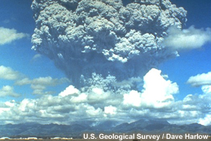 The enormous plume from Mt Pinatubo towers over mountains and fields.