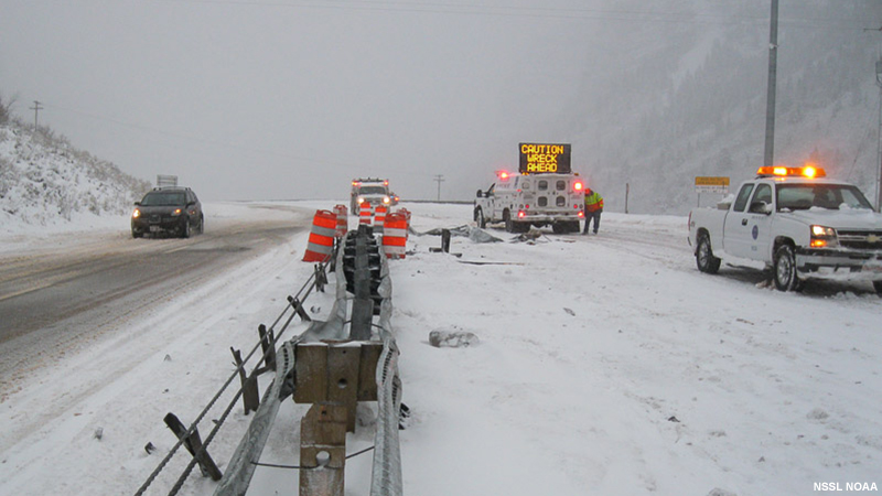 Snow covered road with emergency vehicles.